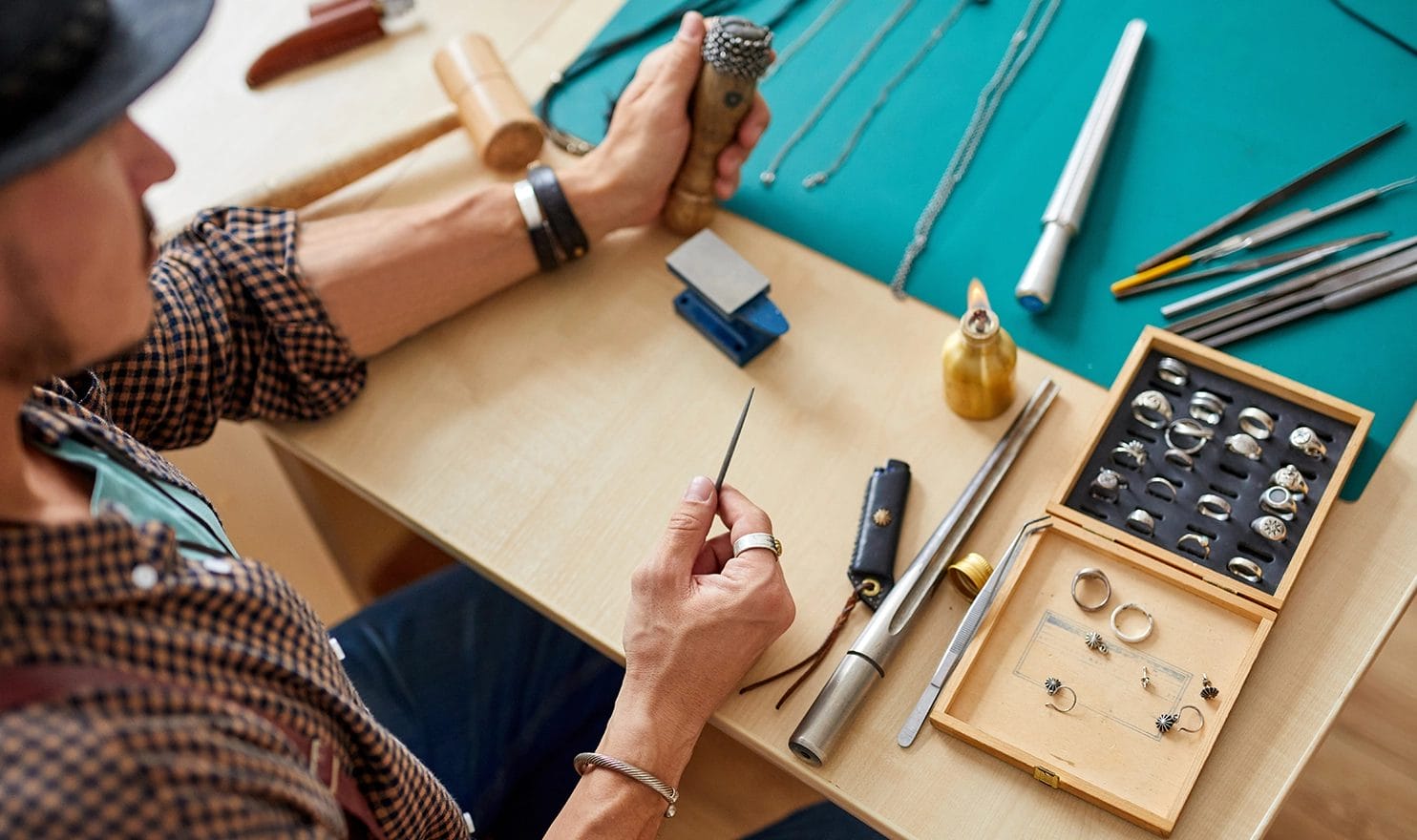 A jewelry maker is working with his tools on a new ring.