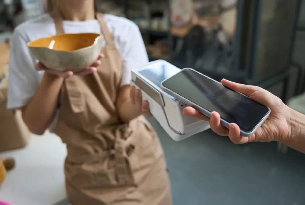 a customer pays by phone through a handheld device in at at artists stall