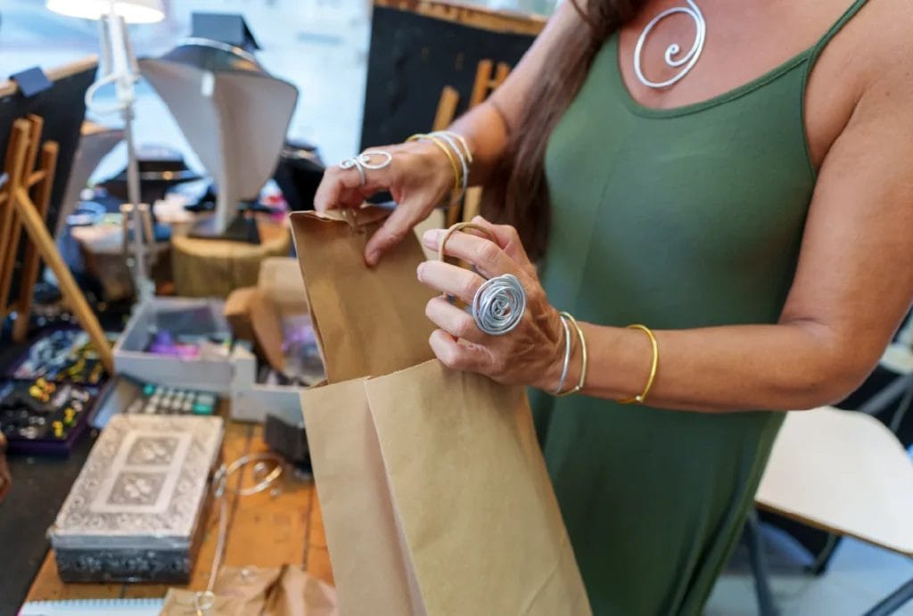 a handmade jewelry maker packaging a customer’s purchase