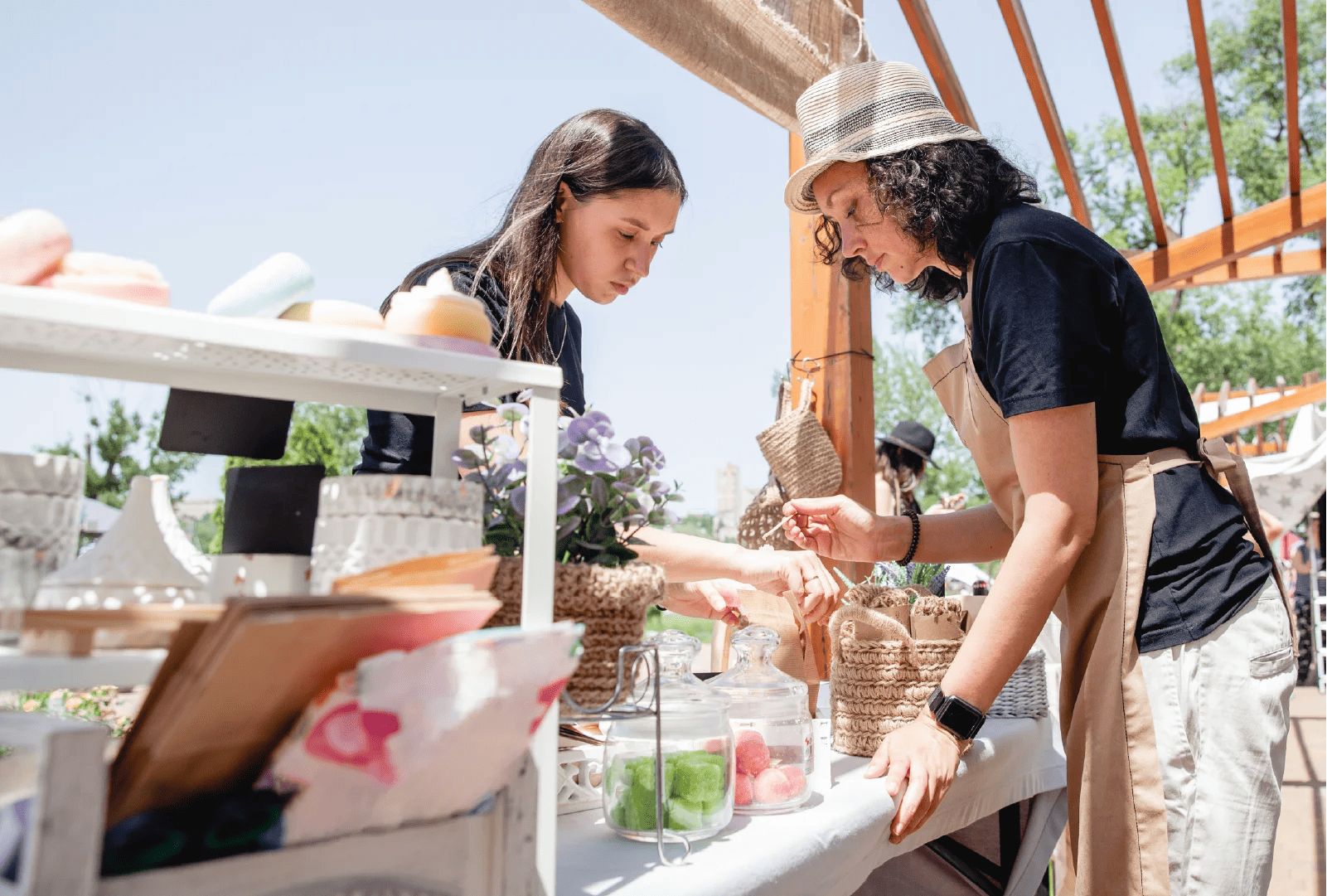 a soap vendor helping a customer at an outdoor market in summer