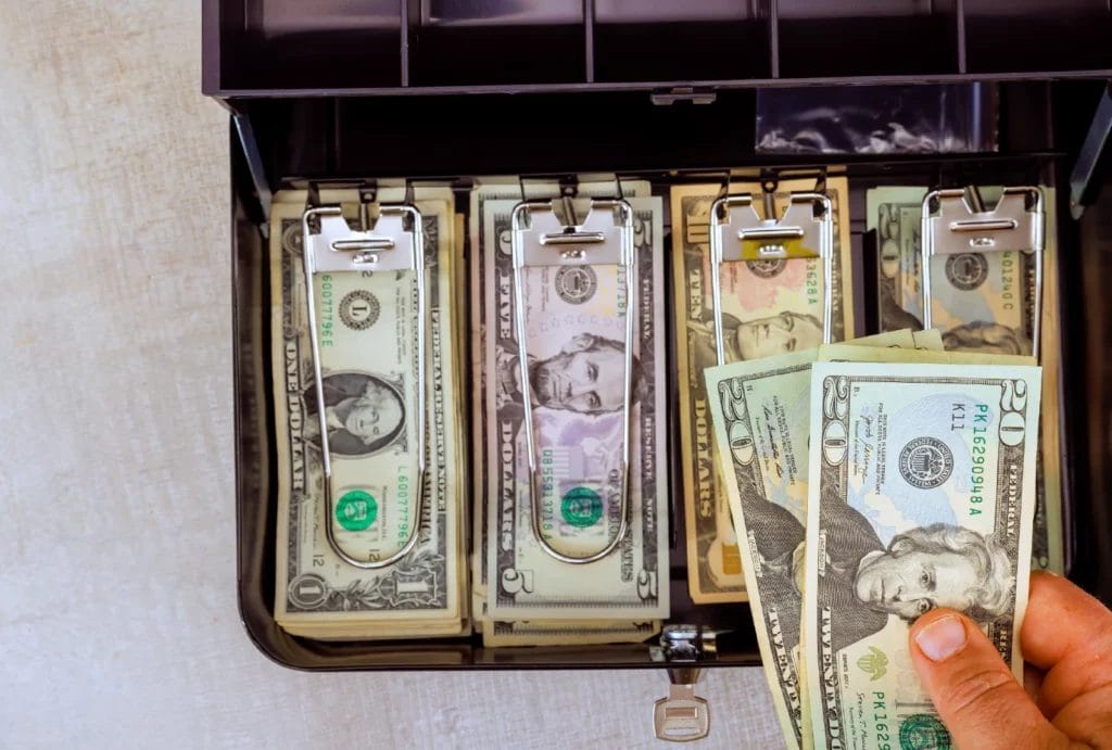 A black cash box with various dollar bills.