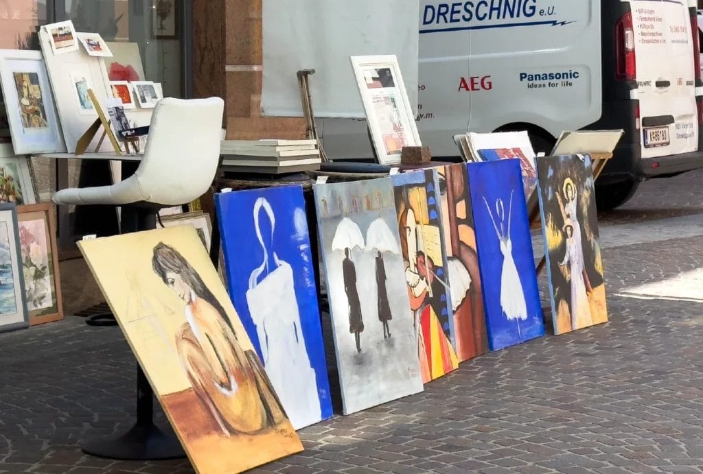 Painted canvases are displayed at an outdoor art market.