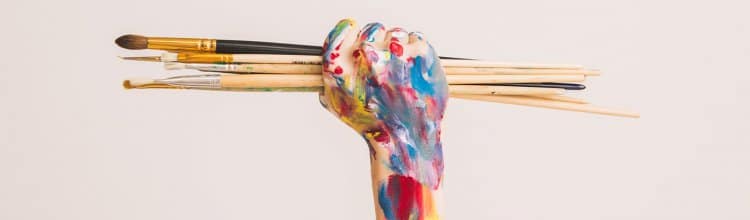 Hand holding paintbrushes.