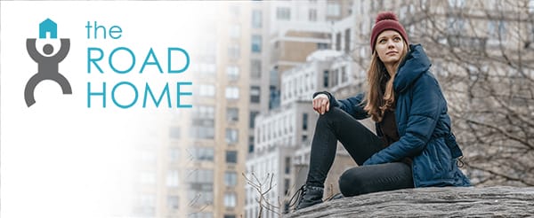 An unhoused person sits with resolve and dignity in a city.