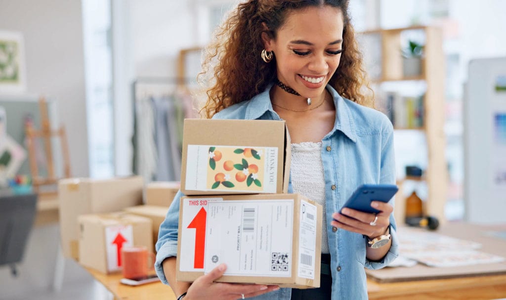 A small creative business owner is holding packages to be sent to customers.