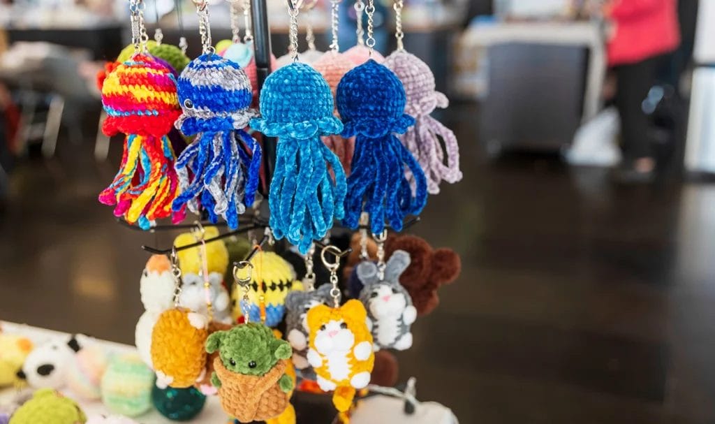 Crocheted and knitted multicolored keychains on display in a vendor booth.