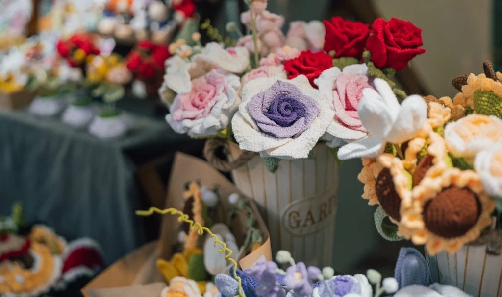 Display of knitted flowers for sale at handmade market.