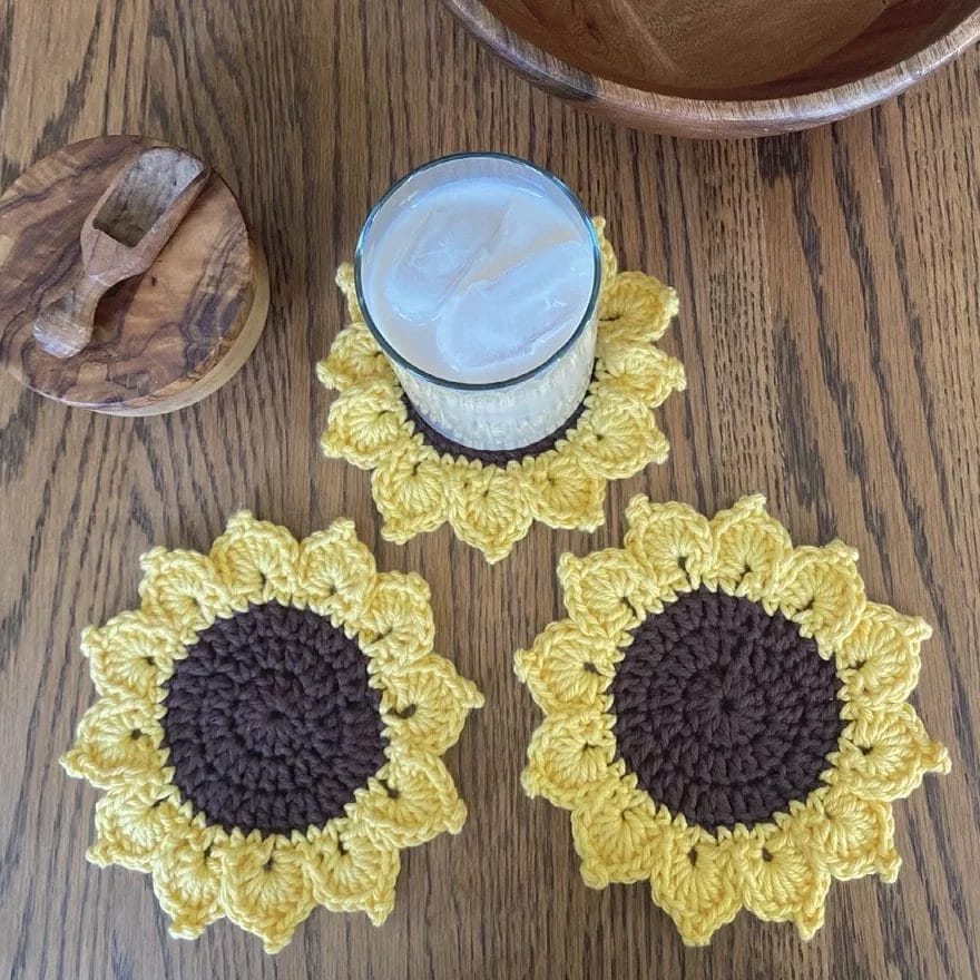 Crochet sunflower coasters on a wood table.