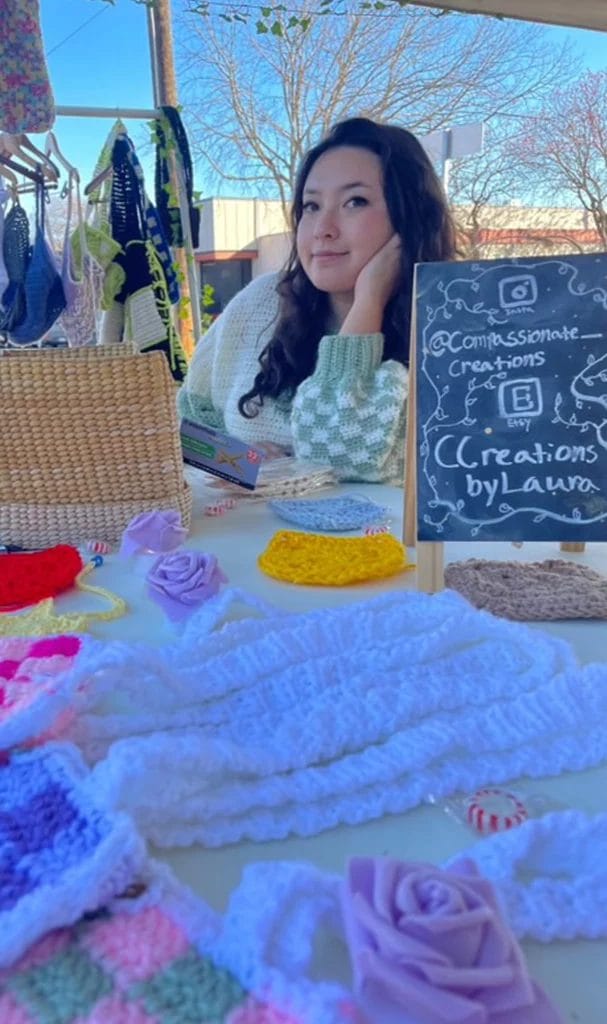Laura posing for a photo while sitting in her crochet craft fair booth.