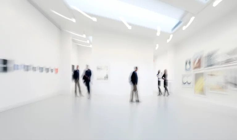 Blurry shot of people observing art in a gallery center.
