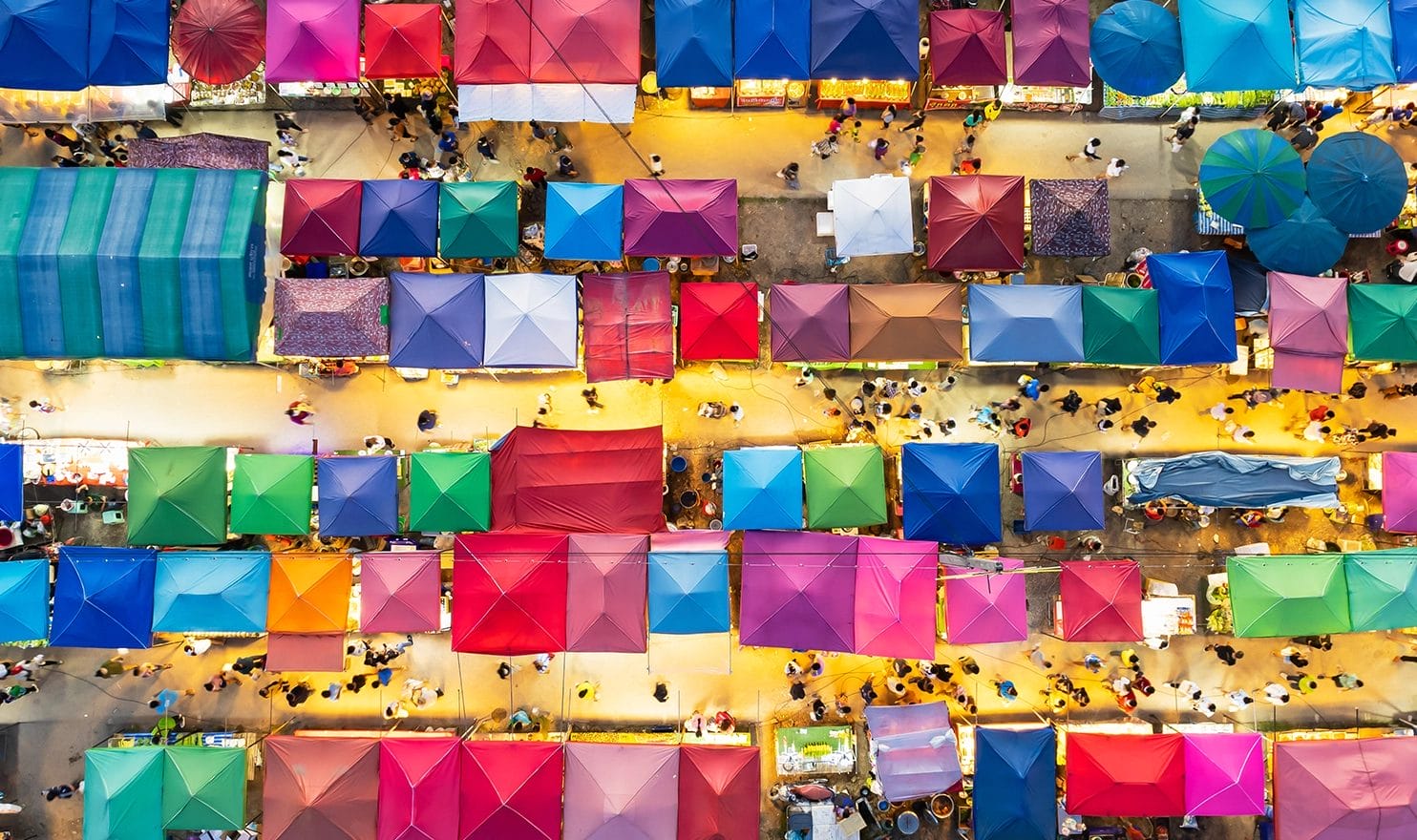 Aerial view of a street market with colorful vendor tents.