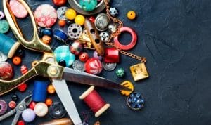 Various tools and accessories for needlework spread across a black background.