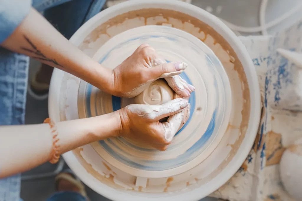A ceramicist shapes a piece of clay on a potter's wheel.