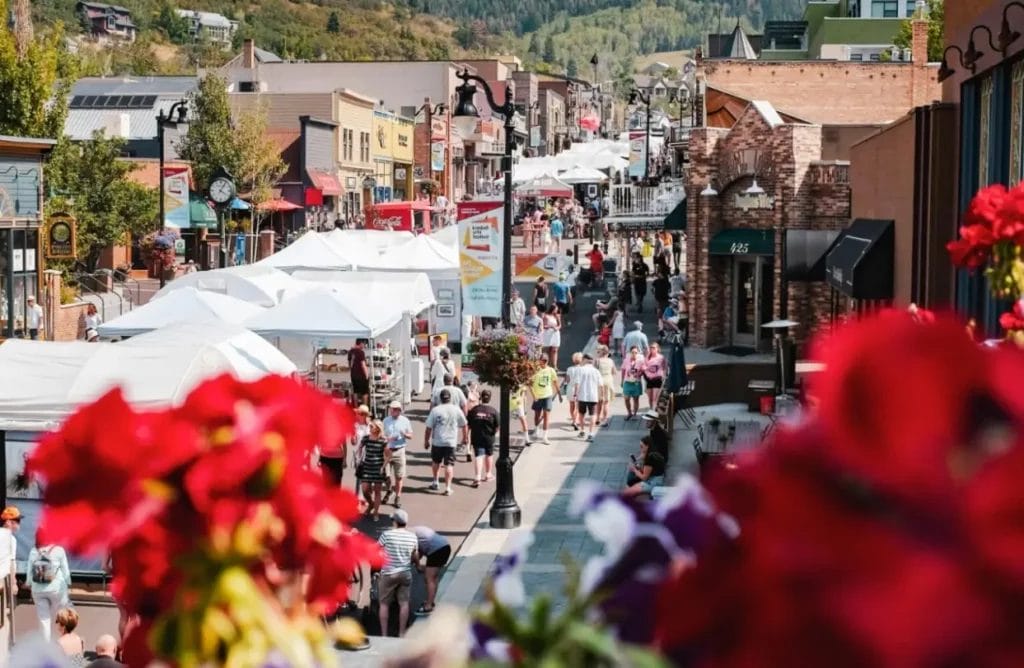 an expanded view of a large outdoor festival with white booths lined up on a city road and customers walking by