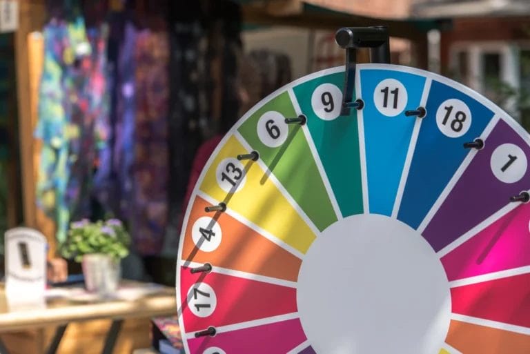 rainbow colored spinning wheel with numbers hung up at a festival