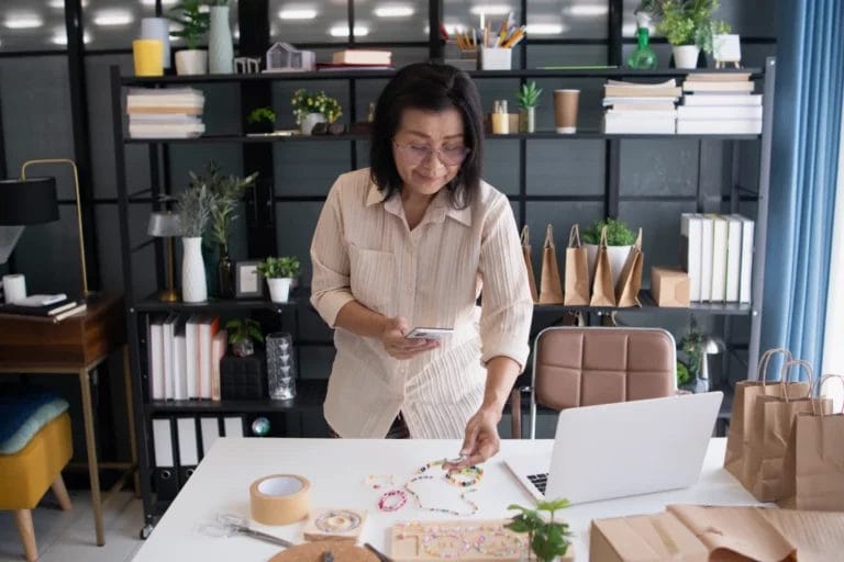 a woman taking photos of handmade beaded jewelry with her mobile phone