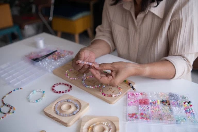 a woman making handmade beaded bracelets