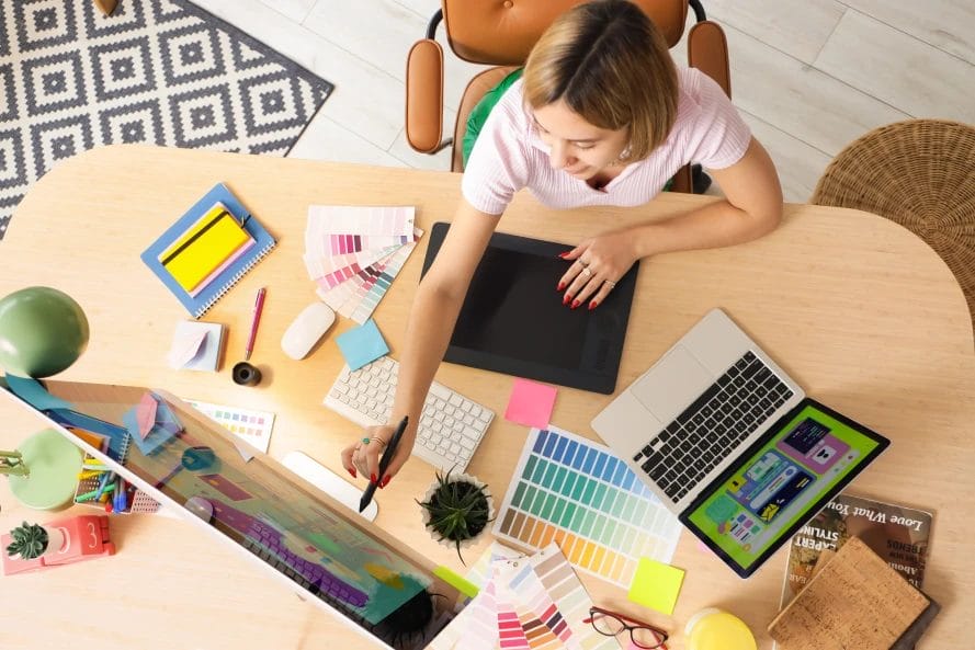 female designer working at a table with color palettes and computers