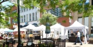 a man walking by an outdoor art festival with white booths