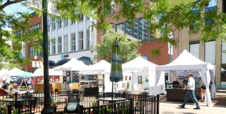 a man walking by an outdoor art festival with white booths