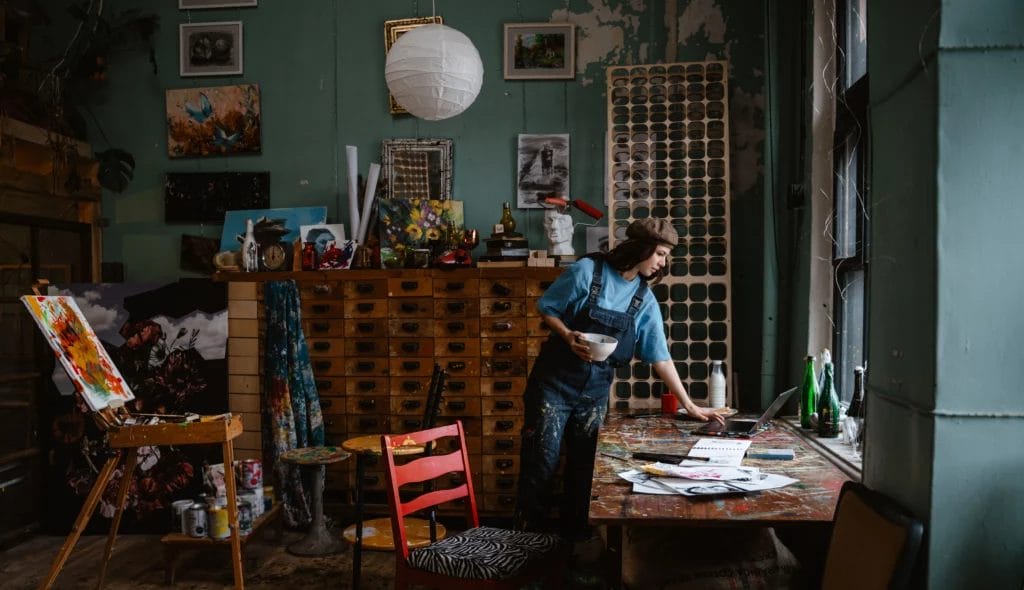 Young woman painter checking her computer inside of her art studio