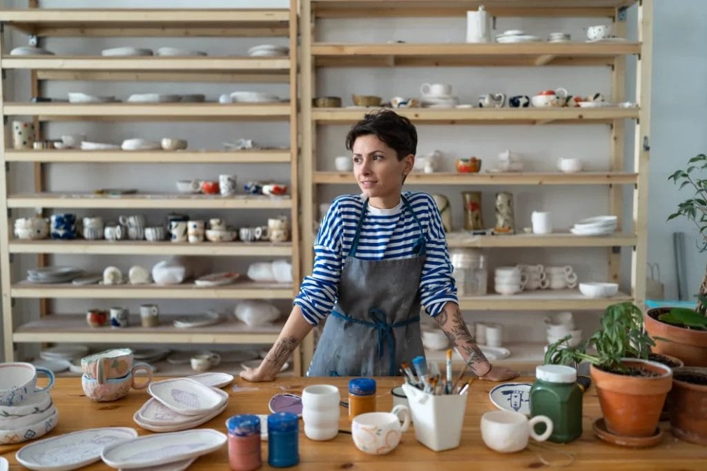 a female pottery artist standing inside her studio