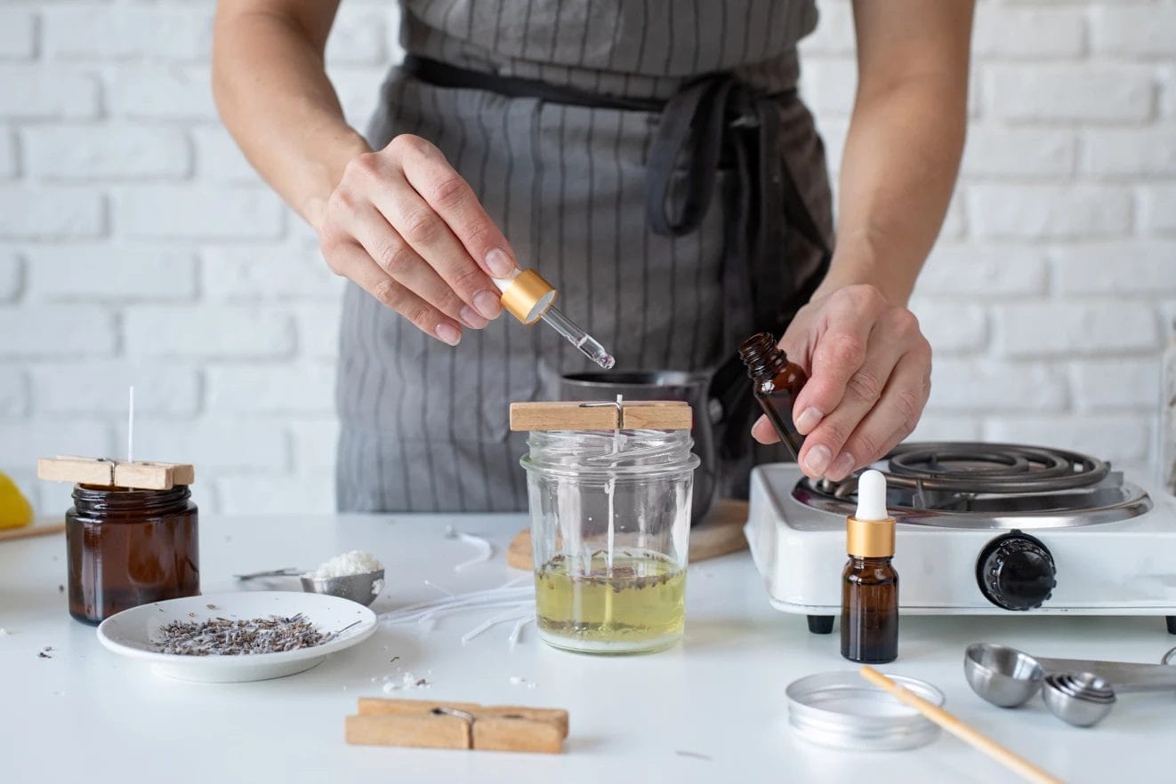 a woman using a dropper to mix fragrance oil into a handmade candle