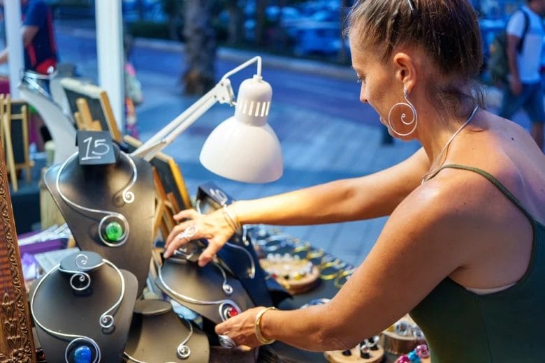a jewelry vendor organizing her display of handmade necklaces