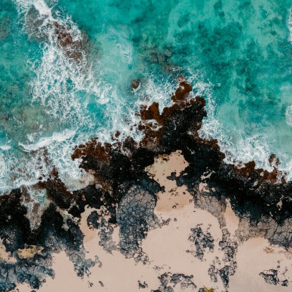 ocean waves crash on a rocky shore in O'ahu, Hawaii